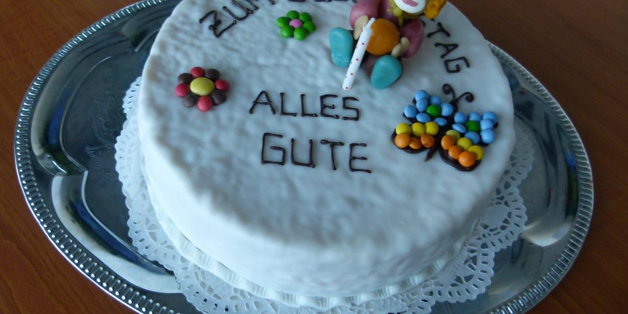 Eine verzierte Torte mit den Worten „Zum Geburtstag alles Gute“.