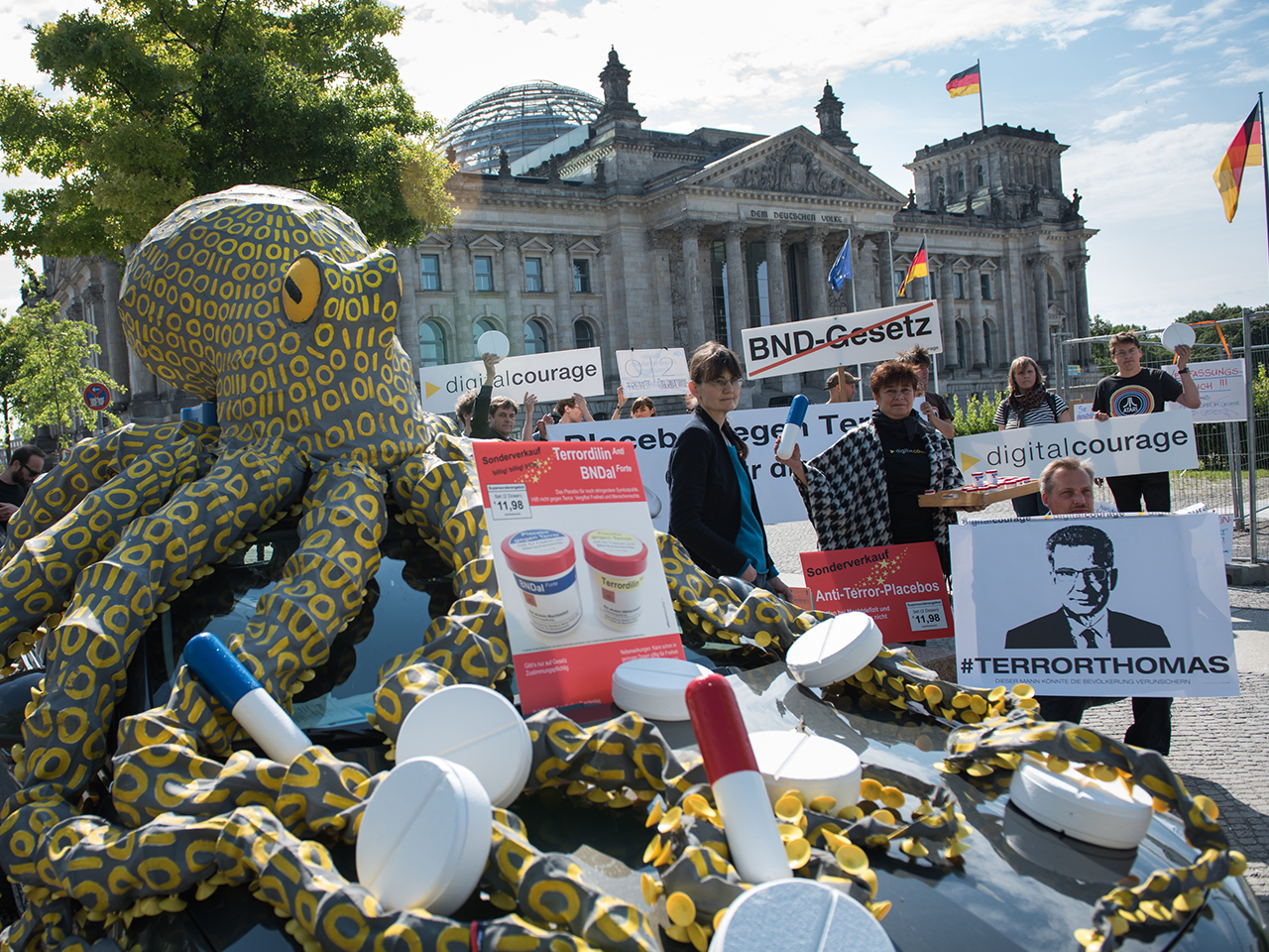 Demonstrant.innen mit der Datenkrake und Placebo-Pillen aus Pappmaché vor dem Berliner Bundestag