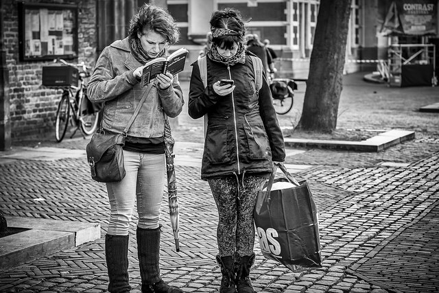 Zwei Frauen suchen nach dem Weg – eine mit Karte, eine mit Smartphone