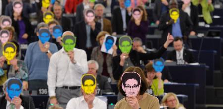 Viele Personen halten sich eine bunte Maske von Edward Snowden vor das Gesicht.