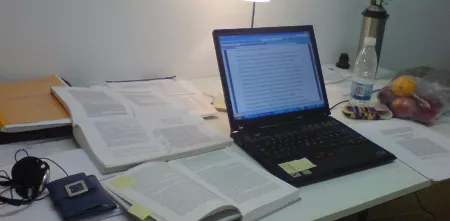 Ein voller Arbeitsplatz mit Laptop und Unterlagen.