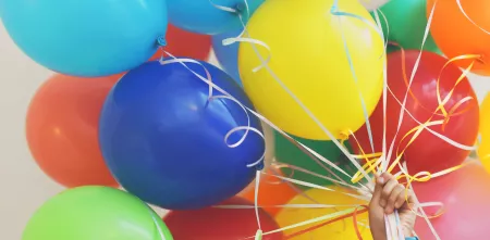 Eine Person hält viele bunte Luftballons fest (Nahaufnahme).