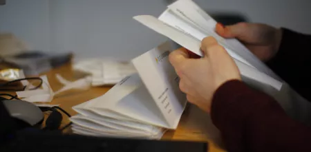 Detailaufnahme: Hände, die einen Brief auseinander falten.