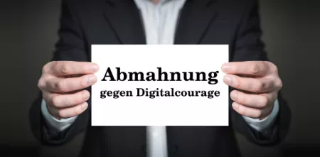 Person mit Anzug hält Schild: Abmahnung für Digitalcourage.