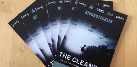 Mehrere Kinokarten zum Film „The Cleaners“ liegen aufgefächert auf einem Tisch.