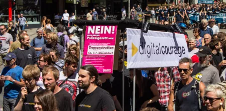 Aktivist.innen mit diversen Bannern auf einer Demo.