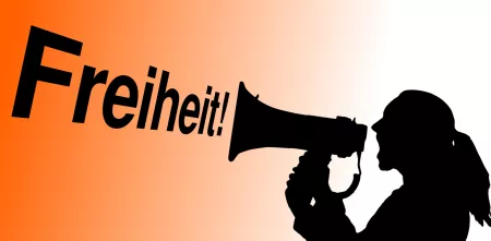 Silhouette einer Person mit einem Megaphon. Daneben das Wort „Freiheit“.