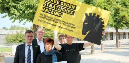 Rena Tangens und padeluun mit drei weiteren Personen, wovon eine ein Schild hochält: „Klage gegen staatliches Hacking“.