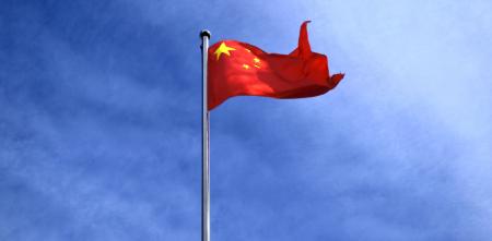 Die Flagge Chinas vor einem blauen Himmel (Froschperspektive).