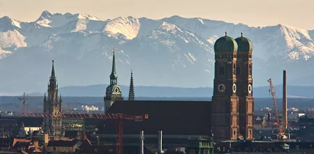 Frauenkirche in München aus der Entfernung. Im Hintergrund die Alpen.