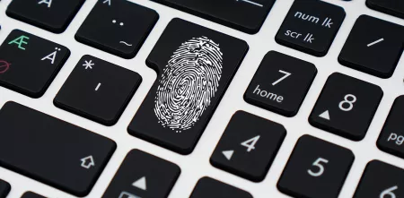 Ein Ausschnitt einer Tastatur mit dem Fokus auf die Enter-Taste, auf der ein Fingerabdruck ist.
