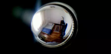 Blick durch eine Linse, dahinter ein Raum in Fisheye-Optik.