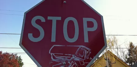 Ein Stop-Schild mit einem Stencil einer Überwachungskamera.