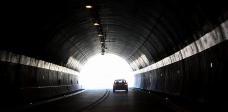 Ein dunkler Tunnel, am Ende ein heller Ausgang mit der Silhouette eines Autos.