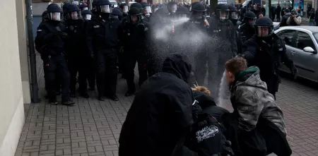 Drei Demonstrant.innen werden von mehreren Polizist.innen mit Pfefferspray besprüht.