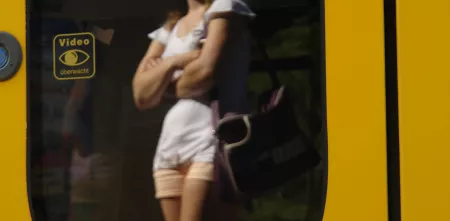 Eine wartende Person spiegelt sich in der Scheibe einer Straßenbahn.