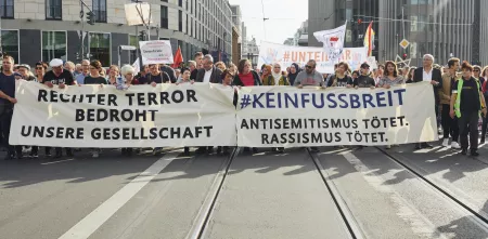 Viele Menschen auf einer Demo mit zwei Transparenten. Transparent 1: „Rechter Terror bedrohnt unsere Gesellschaft“; Transparent 2: „#KEINFUSSBREIT Antisemitismus tötet. Rassimus tötet.“