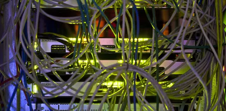 Verwirrte Kabel in einem Serverschrank, grünlich angestrahlt.
