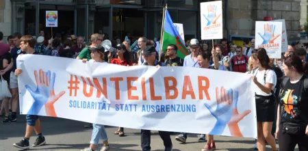 Demonstrant.innen mit einem riesigen „#unteilbar“-Banner.