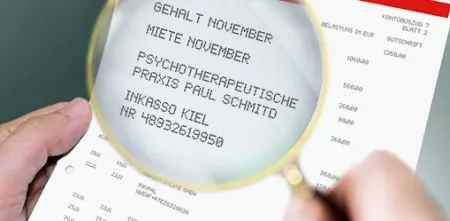 Eine Lupe, die den Text auf einem Kontoauszug vergrößert darstellt.