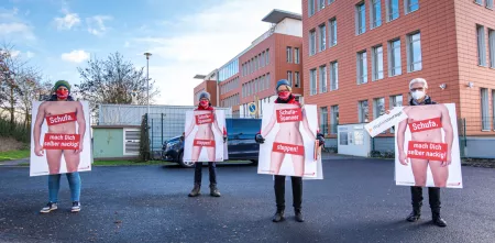 Vier Personen, mit Plakaten von nackten Menschen vor dem Körper. Über Brüste und Geschlechtsorganen steht z. B. „Schufa-Spanner stoppen“.