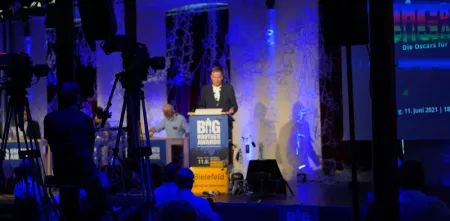 Im Vordergrunde Kameras, im Hintergrund Andreas Liebold, Moderator der Big Brother Awards an einem Rednerpult