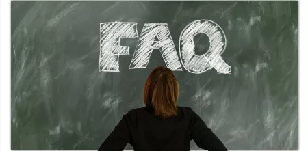 Eine Person, die vor einer Tafel steht, auf der FAQ steht.