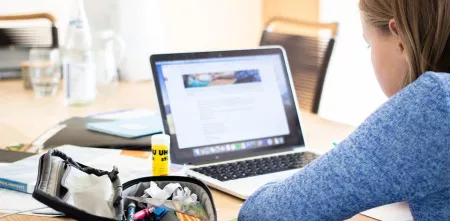 Mädchen macht Schulaufgaben am Laptop