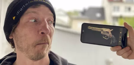 Mann wird von Revolverfoto bedroht, das auf einem Smartphone angezeigt wird.