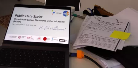 Foto vom Display eines Laptops mit einer Begrüßungsfolie mit der Überschrift "Public Data Sprint, Gemeinsam soziale Netzwerke weiter erforschen"