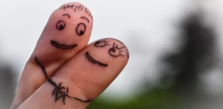 Zwei Finger haben verliebte Gesichter aufgemalt und flirten angeschmiegt miteinander.