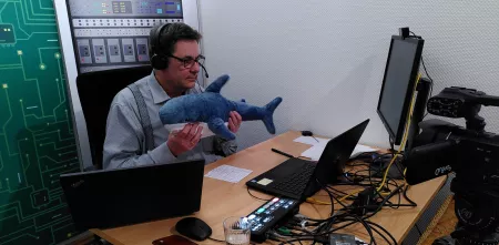 padeluun hält einen Online-Vortrag – in seinen Händen streckt er einen Plüschhai Richtung Webcam.