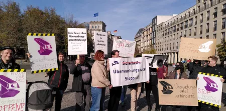 Leute mit Schildern und Transparenten demostrieren gegen das Sicherheitspaket.