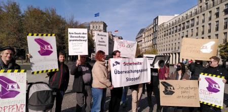 Leute mit Schildern und Transparenten demostrieren gegen das Sicherheitspaket.