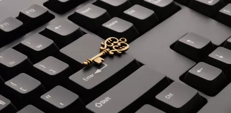 Ausschnitt einer schwarzen Tastatur. Darauf liegend ein goldener Schlüssel.