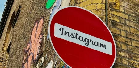 Detailaufnahme des Straßenschildes „Keine Durchfahrt“ (roter Kreis mit weißem Querbalken). Im weißen Bereich steht: „Instagram“. Im Hintergrund eine Klinkerwand mit Graffiti.