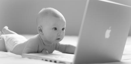 Ein Baby, das auf einen Laptop-Bildschirm starrt (schwarz-weiß).