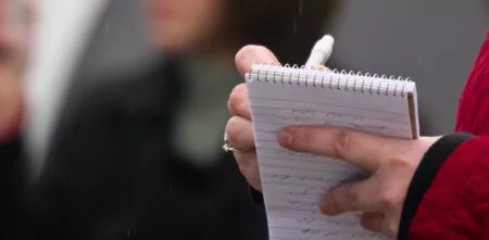 Detailaufnahme von einer Person die etwas auf einen Block schreibt.