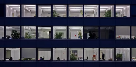 Viele Fenster eines Hochhauses, die nachts beleuchtet sind.