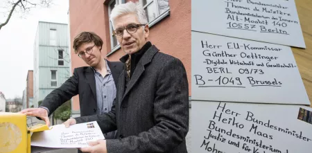 Friedemann Ebelt und Detlev Sieber werfen einen Brief in einen Briefkasten. Links daneben drei Detailaufnahmen von drei Briefen inkl. Adresse.