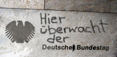 Hauswand mit dem Bundesadler und „Deutscher Bundestag“. Darüber nachträglich hinzugefügt: „Hier überwacht der“.