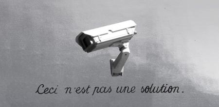 Illustration: Eine Überwachungskamera. Darunter der Text: „Ceci c'est ne pas une solution“.