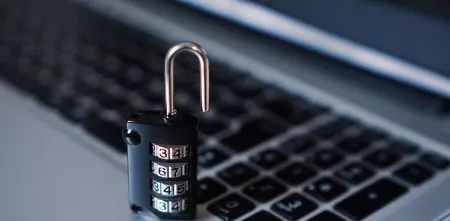 Ein Vorhängeschloss auf einer Laptoptastatur (Detailaufnahme).