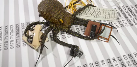 Eine Datenkrake, die in jedem Tentakel einen technischen Gegenstand hält (Tastatur, Telefon, Fotoapparat, Handy, ...).