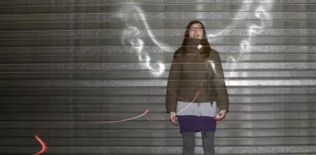 Eine Person, die vor einer Wand steht, auf der Flügel gemalt sind.