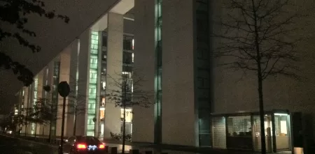 Ein großes Gebäude, teils beleuchtet, bei Nacht.