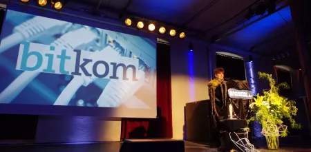 Rena Tangens am Redner.innenpult der BBAs 2017. Im Hintergrund das Logo der bitkom.