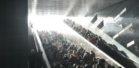 Viele Menschen auf einer breiten Treppe und Rolltreppe.