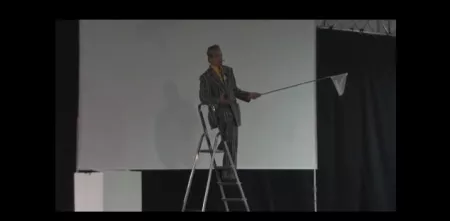Eine Person auf einer Leiter mit einer kleinen Fahne in der Hand.