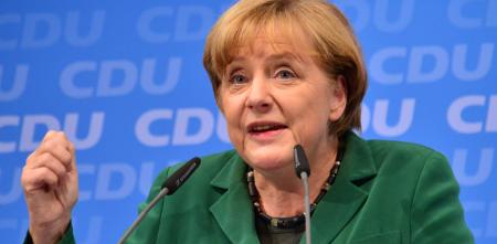 Portraitaufnahme von Angela Merkel, die an einem Mikrofon spricht.